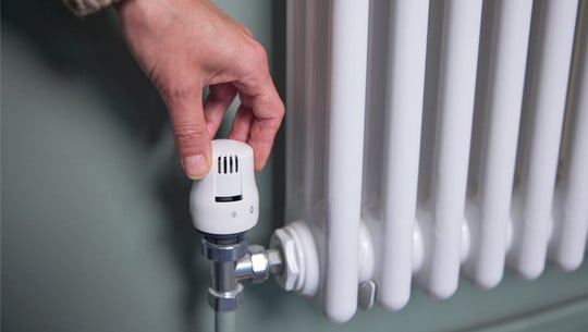 Gasheizung kaputt: Was tun? Hand dreht an Heizkörper-Thermostat