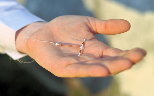 Holding an IUD birth control device in hand Die Kupferspirale ist eine hormonfreie Verhütungsmethode.