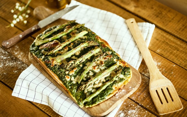 homemade pizza with asparagus and spinach on a rustic wooden table Grüner Spargel passt auch gut auf Pizza.