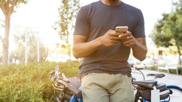 handyfahrrad-e-linkedinsalesnavigator-220408-1280x800 Person mit Handy lehnt an einem Fahrrad