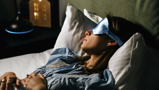 Frau mit Schlafmaske im Bett Frau mit Schlafmaske im Bett