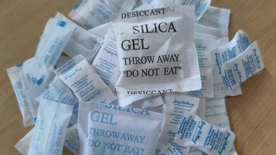 Käse schimmelt nicht dank Silica-Gel? Social-Media-Tipp im Check Mehrere kleine Beutel mit Silicagel, beschriftet mit Warnhinweisen wie "DESICCANT", "SILICA GEL" und "DO NOT EAT", liegen auf einer Holzoberfläche.