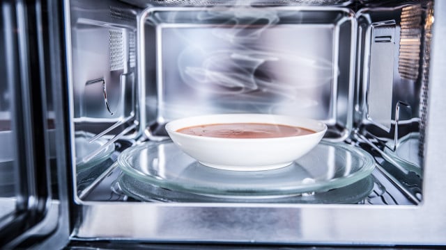 Inside view of new clean staniless microwave oven with a tomato soup in white plate auftauen mikrowelle