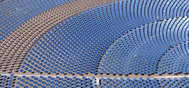 Deutschland hinkt hinterher: Wie China den Markt für grüne Technologie dominiert (Foto: Hu Huhu/Xinhua/dpa) Luftaufnahme eines großen Solarthermiekraftwerks mit zahlreichen kreisförmig angeordneten, blauen Spiegeln, die das Sonnenlicht bündeln. Die Spiegel sind auf einer sandigen Fläche installiert und reflektieren den Himmel.