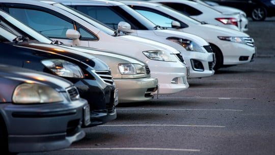 autoflotte-dienstwagen-colourbox-251110 Reihe von geparkten Autos, hauptsächlich in Weiß und Schwarz, auf einem asphaltierten Parkplatz, Frontansicht der Fahrzeuge sichtbar.