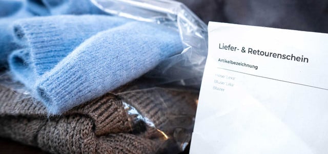 Warum die Zahl der Retouren nicht sinkt: Diese Artikel machen 90 Prozent aus (Foto: Sina Schuldt/dpa) Zwei zusammengefaltete Strickpullover in blauer und brauner Farbe, verpackt in einer transparenten Plastiktüte, daneben ein Lieferschein mit der Überschrift "Liefer- & Retourenschein" und einer Liste von Artikelbezeichnungen.