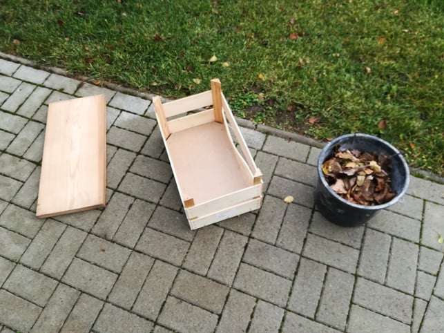 Processed with VSCO with preset Ein Holzbrett, eine Obstkiste und Herbstlaub: die Grundmaterialien für das Igelhaus.