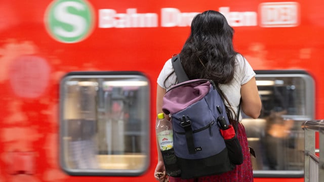 Eine Frau steht auf einem Bahnsteig vor einer S-Bahn