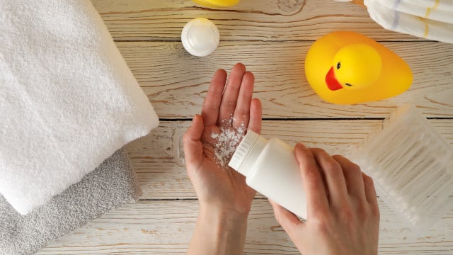Mom applying talc powder from plastic tube. Baby hygiene talkum