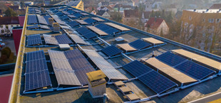 Solarmodule stehen auf einem Flachdach eines Mehrfamilienhauses