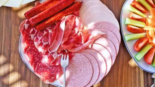 Jeden Tag Wust essen: Das sind die Folgen Verschiedene Wurst- und Schinkensorten, darunter Salami, Kochschinken, Mortadella und dünn geschnittener Rohschinken, auf einem weißen Teller
