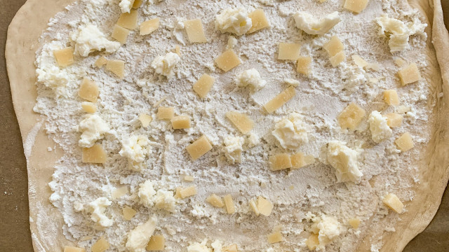 Spread the dough thinly and spread Parmesan and mozzarella on top.