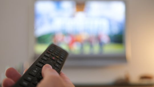 Was sich im November ändert Eine Hand bedient eine Fernbedienung für ein TV-Gerät.