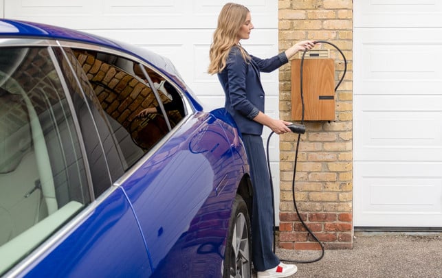 e-auto-laden-wallbbox-us-andersenev-251110 Eine Frau lädt ein E-Auto und steckt das Ladekabel in eine Wallbox