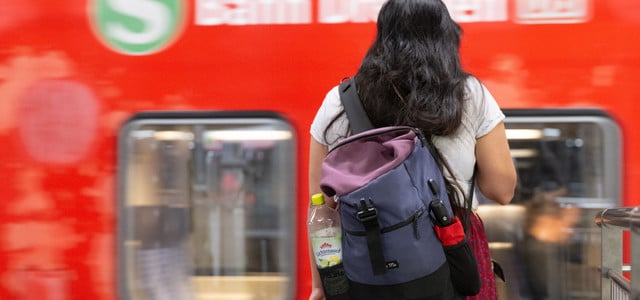 Eine Frau steht auf einem Bahnsteig vor einer S-Bahn