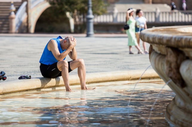 Ein Mann kühlt sich an einem Brunnen ab. Ein Mann kühlt sich an einem Brunnen ab.