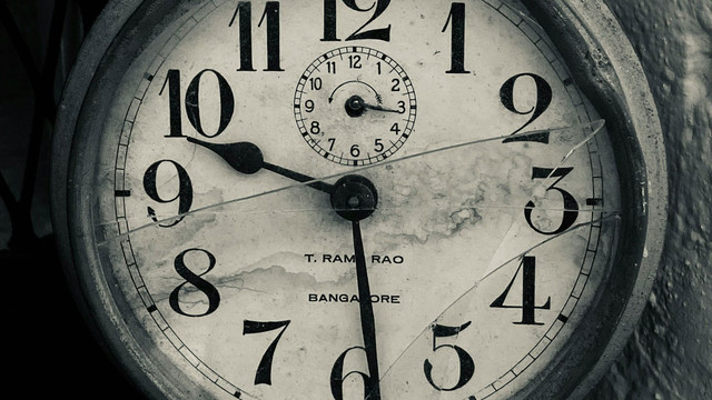 "Hilfe, ich habe keine Zeit!" - 5 Expertinnen-Tipps gegen Zeitmangel Alte, runde Wanduhr mit großen schwarzen Zahlen auf weißem Zifferblatt, das durch Risse und Flecken gezeichnet ist. Die Uhr zeigt die Zeit 10:29, mit einem kleineren Zifferblatt oben für Sekunden. Auf dem Zifferblatt steht "T. RAM RAO" und "BANGALORE".