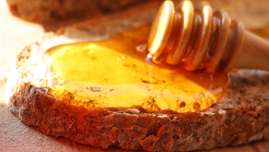 Jeden Tag Honig essen: Die Folgen Scheibe Vollkornbrot mit einer großzügigen Schicht goldgelbem Honig