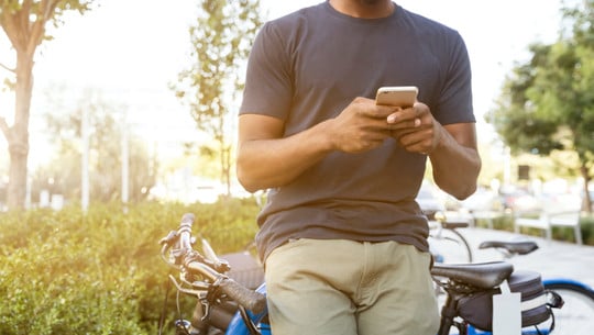 handyfahrrad-e-linkedinsalesnavigator-220408-1280x800 Person mit Handy lehnt an einem Fahrrad