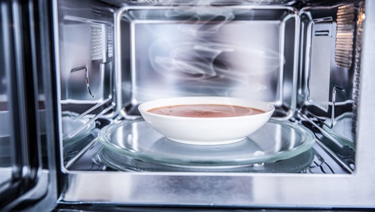 Inside view of new clean staniless microwave oven with a tomato soup in white plate auftauen mikrowelle