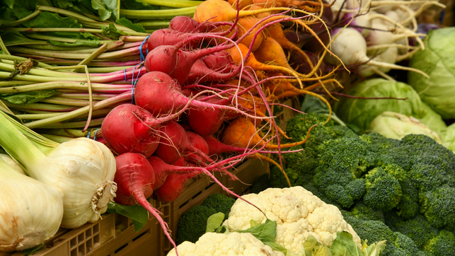 shelley-pauls-h3lcKaOZWPc-unsplash Frisches Gemüse, darunter rote und gelbe Rüben mit langen Wurzeln, Knoblauchknollen, Brokkoli, Blumenkohl und grüne Kohlköpfe, in Kisten angeordnet.