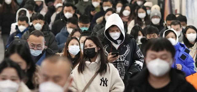 China, Peking: Menschen mit Mund-Nasen-Schutz gehen während der Hauptverkehrszeit durch eine U-Bahn-Station.