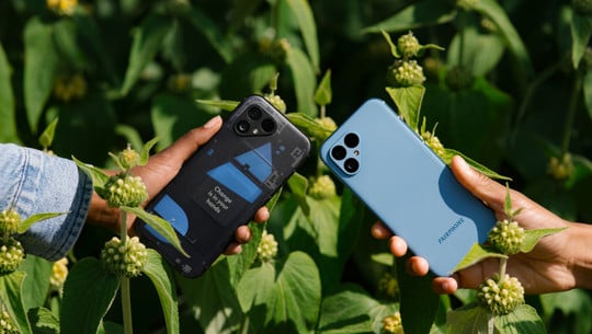 Fairphone 5 Test Zwei Hände in einem hellen, von Pflanzen bewachsenen Feld. Sie halten jeweils ein Fairphone 5 Mobiltelefon.