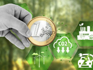 "Effektiv Spenden" statt CO2-Kompensation: Kann 1 Euro wirklich 1 Tonne CO2 einsparen? Hand hält eine 1-Euro-Münze vor einem unscharfen grünen Hintergrund, umgeben von grünen Hexagonen mit Symbolen für Windenergie, CO2-Reduktion, nachhaltige Industrie und Elektrofahrzeuge.