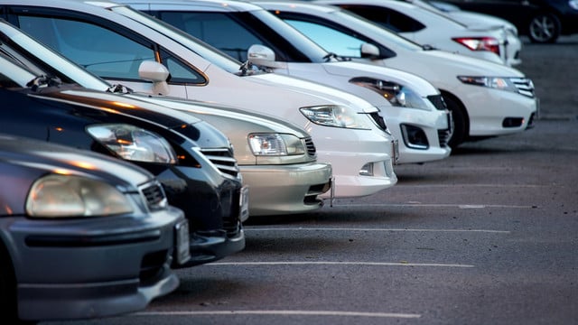 autoflotte-dienstwagen-colourbox-251110 Reihe von geparkten Autos, hauptsächlich in Weiß und Schwarz, auf einem asphaltierten Parkplatz, Frontansicht der Fahrzeuge sichtbar.