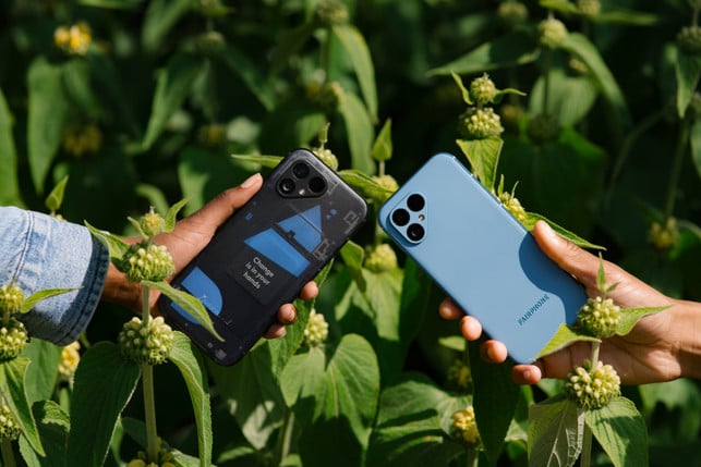 Fairphone 5 Test Zwei Hände in einem hellen, von Pflanzen bewachsenen Feld. Sie halten jeweils ein Fairphone 5 Mobiltelefon.