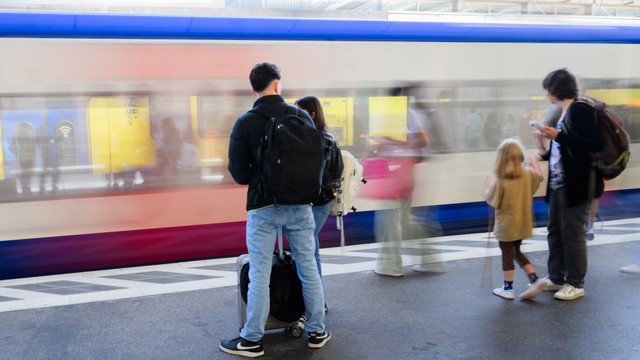 Personen mit Gepäck auf einem Bahnsteig vor einer Bahn Personen mit Gepäck auf einem Bahnsteig vor einer Bahn