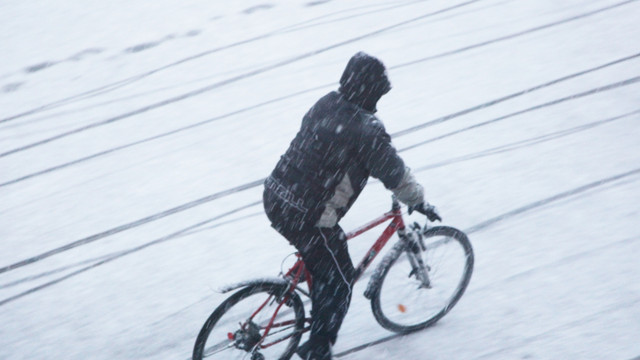 radfahren-schnee-winter-cb-260128 Mann fährt im Schnee Fahrrad, der Weg ist schneebedeckt