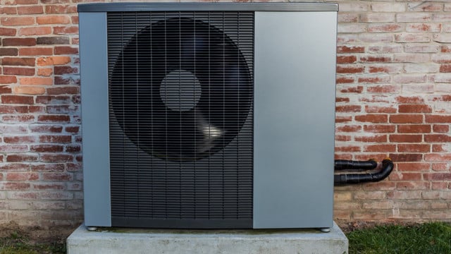 Wärmepumpe reinigen Wärmepumpe vor einer Hauswand