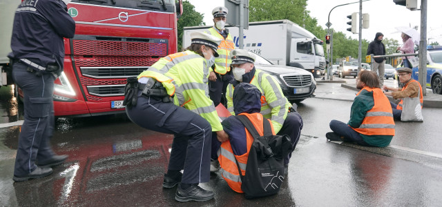 Polizisten tragen einen Demonstranten der Letzten Generation weg, der eine Hauptverkehrsstraße in Stuttgart blockiert hat.