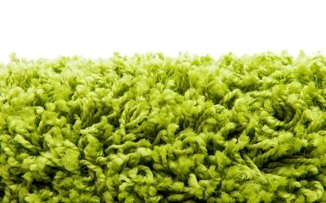 Close up of green yarn carpet Hartnäckige Flecken in Hochflortepppichen kannst du auch mit Hausmitteln entfernen.