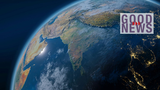 Historisches Votum: UN verpflichten Staaten zu Klimaschutz Satellitenansicht der Erde mit Fokus auf den indischen Subkontinent, dem Nahen Osten und Teilen Afrikas, beleuchtet von Sonnenlicht und Stadtlichtern bei Nacht, mit dem Schriftzug „GOOD NEWS“ in lila und roten Pfeilen im rechten Bildbereich.