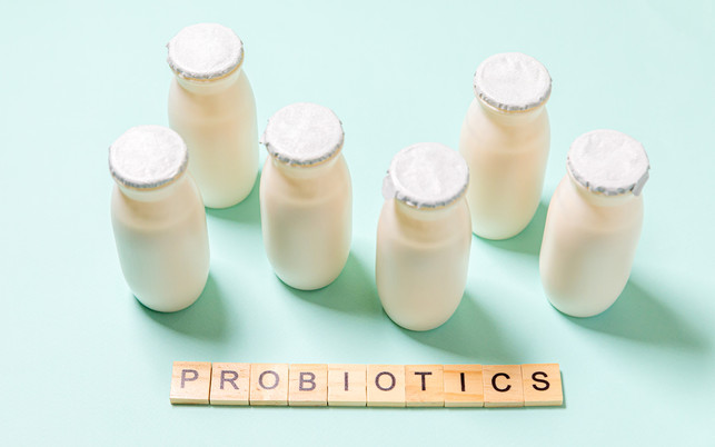 Small bottles with probiotics and prebiotics dairy drink on blue background. Production with biologically active additives. Fermentation and diet healthy food. Bio yogurt with useful microorganisms. Bifidobakterien stecken nicht nur in beworbenen Produkten.