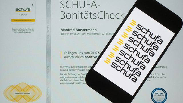 Schufa, Zeitumstellung und Rente - das ändert sich im März 2026 Ein SCHUFA-Bonitätscheck-Dokument mit dem Namen Manfred Mustermann, Geburtsdatum 06.06.1966, und einer Adresse. Auf dem Dokument sind das SCHUFA-Logo, ein offizielles Zertifikat mit dem Datum 01.07.2020 und der Text „Wir schaffen Vertrauen“ zu sehen. Ein Smartphone liegt auf dem Dokument und zeigt mehrfach das SCHUFA-Logo in Schwarz und Gelb.