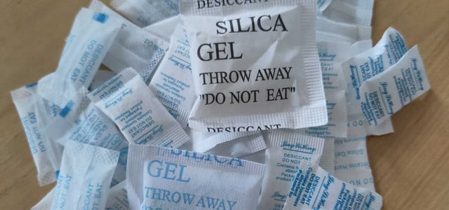 Käse schimmelt nicht dank Silica-Gel? Social-Media-Tipp im Check (Foto: VZ NRW/dpa-tmn) Mehrere kleine Beutel mit Silicagel, beschriftet mit Warnhinweisen wie "DESICCANT", "SILICA GEL" und "DO NOT EAT", liegen auf einer Holzoberfläche.