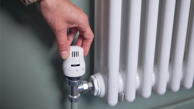 Gasheizung kaputt: Was tun? Hand dreht an Heizkörper-Thermostat