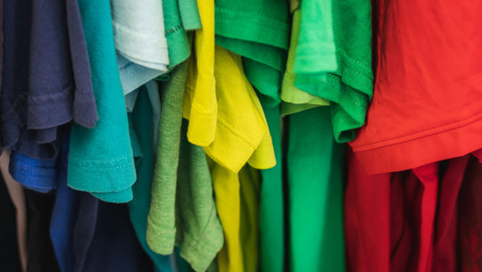 Spart Geld und Emissionen: Dieser praktische Skill lässt mich nachhaltiger leben Nahaufnahme von hängenden T-Shirts in verschiedenen Farben, darunter Blau, Türkis, Hellblau, Gelb, Grün und Rot. Nähen zu lernen war für Redakteurin Kathi ein wichtiger Skill, um Kleidung nachhaltiger zu konsumieren.