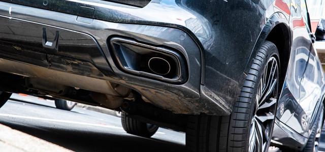 „Selbst kaputtgemacht“: Warum E-Mobilität in Deutschland so langsam vorankommt (Foto: Alicia Windzio/dpa) Heckansicht eines schwarzen Autos mit Fokus auf den Auspuff