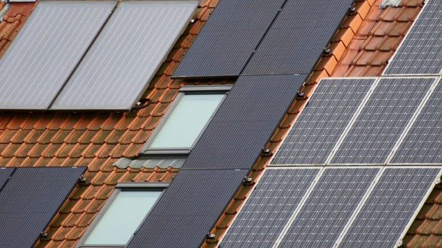 Solarthermie: Mit diesen Kosten musst du rechnen Dach mit roten Ziegeln, auf dem mehrere Solarpaneele und zwei Dachfenster installiert sind.