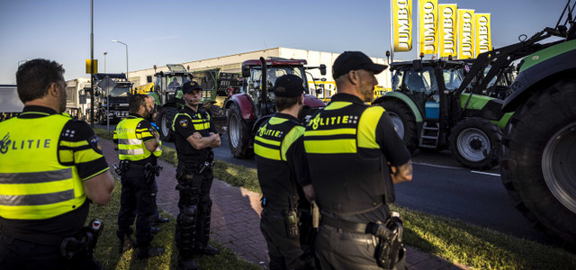 Niederlande, Veghel: Polizisten stehen neben Traktoren, die ein Verteilzentrum der Supermarktkette Jumbo blockieren. Die Bauern sind wegen Auflagen zur Reduzierung des Stickstoff-Ausstoßes verärgert.