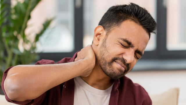 unhappy man suffering from neck pain at home Steifer Hals