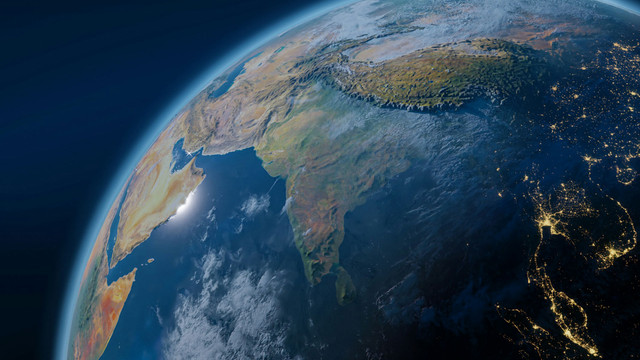 UN-Bericht kündigt neues Zeitalter an Satellitenansicht der Erde mit Fokus auf den indischen Subkontinent, den Arabischen Halbinsel und Teile Südostasiens. Die Küstenlinien, Gebirge und Wolkenformationen sind deutlich sichtbar. In der rechten Bildhälfte sind Stadtlichter in der Nacht erkennbar, die die Bevölkerungszentren in Südostasien markieren.