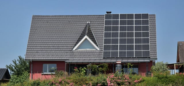 Einfamilienhaus, auf dem Solarpaneele installiert sind. Der Himmel ist klar und blau.