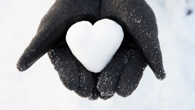 Close Up Of Hands Holding Heart Made Out Of Snow beheizbare kleidung