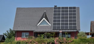 Einfamilienhaus, auf dem Solarpaneele installiert sind. Der Himmel ist klar und blau.