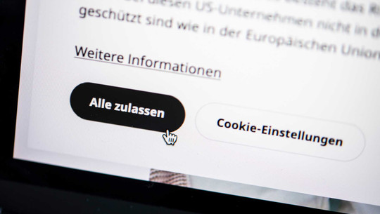 Dark Patterns manipulieren uns beim Einkauf: Kann man sich schützen? Ausschnitt einer Webseite mit einem Cookie-Hinweis. Zu sehen sind zwei Buttons: ein schwarzer Button mit weißer Schrift „Alle zulassen“ und ein weißer Button mit schwarzer Schrift „Cookie-Einstellungen“. Darüber steht ein Link mit dem Text „Weitere Informationen“. Ein Mauszeiger in Form einer Hand zeigt auf den Button „Alle zulassen“.